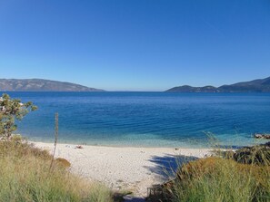 A beach with clear blue water, pebbly shore, and distant mountains. - Spacious villa with privacy and mountain views, near Agia Efimia & Myrtos beach (Makriotika, Kefalonia)