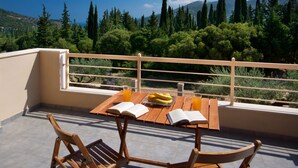 A balcony with a wooden table, two chairs, and an open book. - Spacious villa with privacy and mountain views, near Agia Efimia & Myrtos beach (Makriotika, Kefalonia)