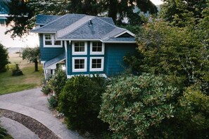 A two-story house with a dark blue exterior, a covered porch, and a well-maintained lawn.