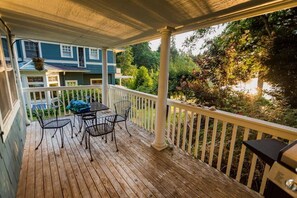 A wooden deck with a covered area, a table, and chairs.