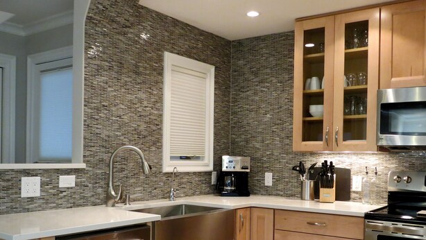A kitchen with a built-in dishwasher, stainless steel appliances, wooden cabinets, and a tiled backsplash.