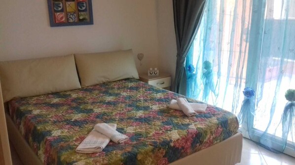 Una cama bien hecha con una colcha estampada y dos toallas dobladas.