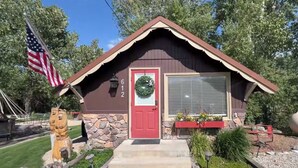 Un petit bâtiment avec une porte rouge, des fondations en pierre et un drapeau américain.