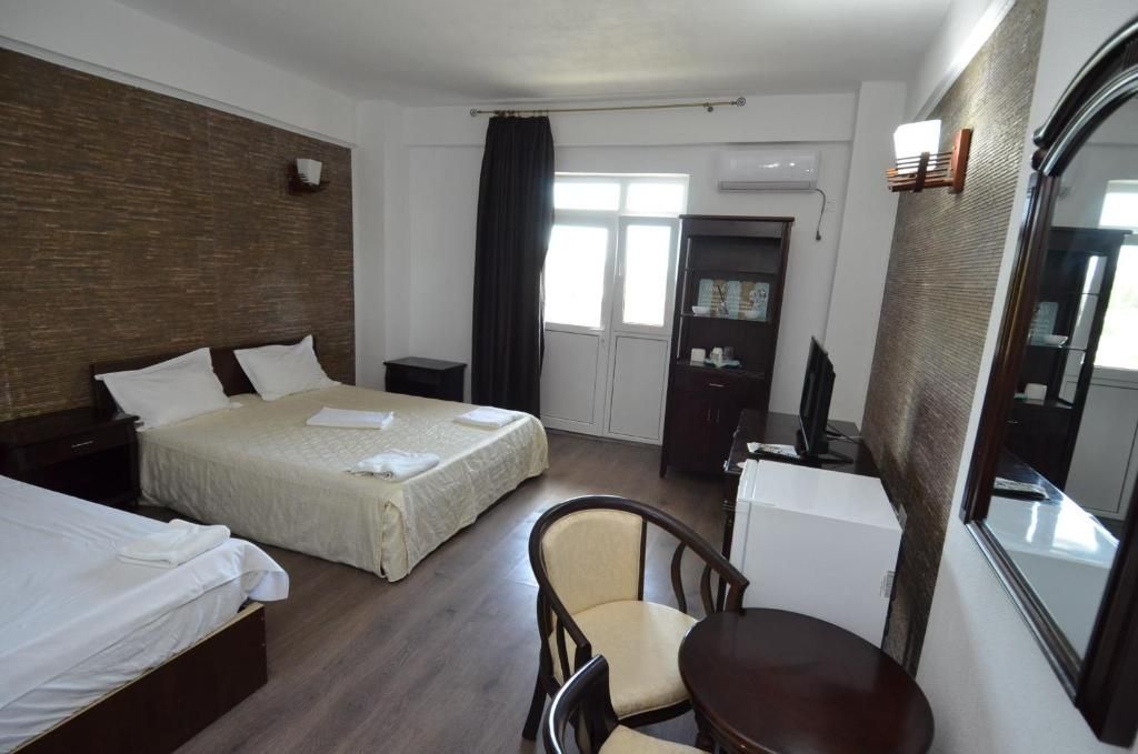 A hotel room with two beds, a desk, a chair, and a large mirror.