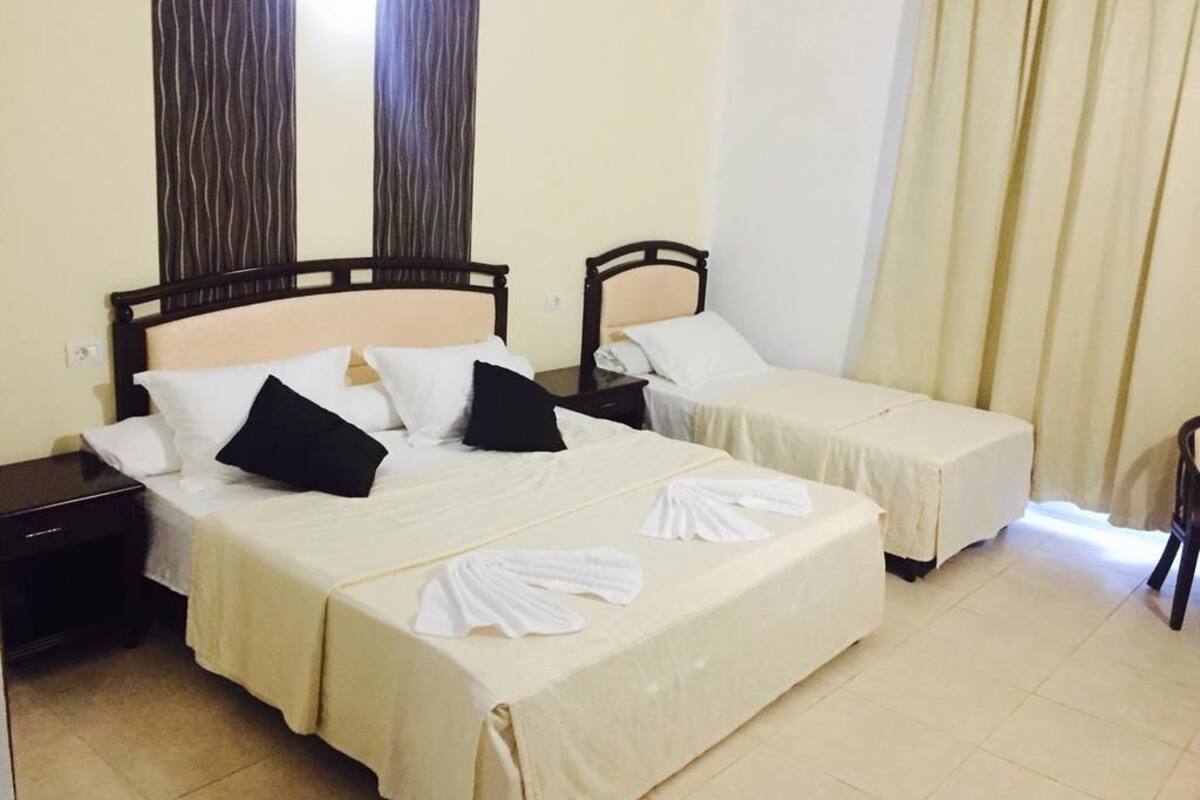 A hotel room with two beds, each with a headboard, a nightstand, and a chair.