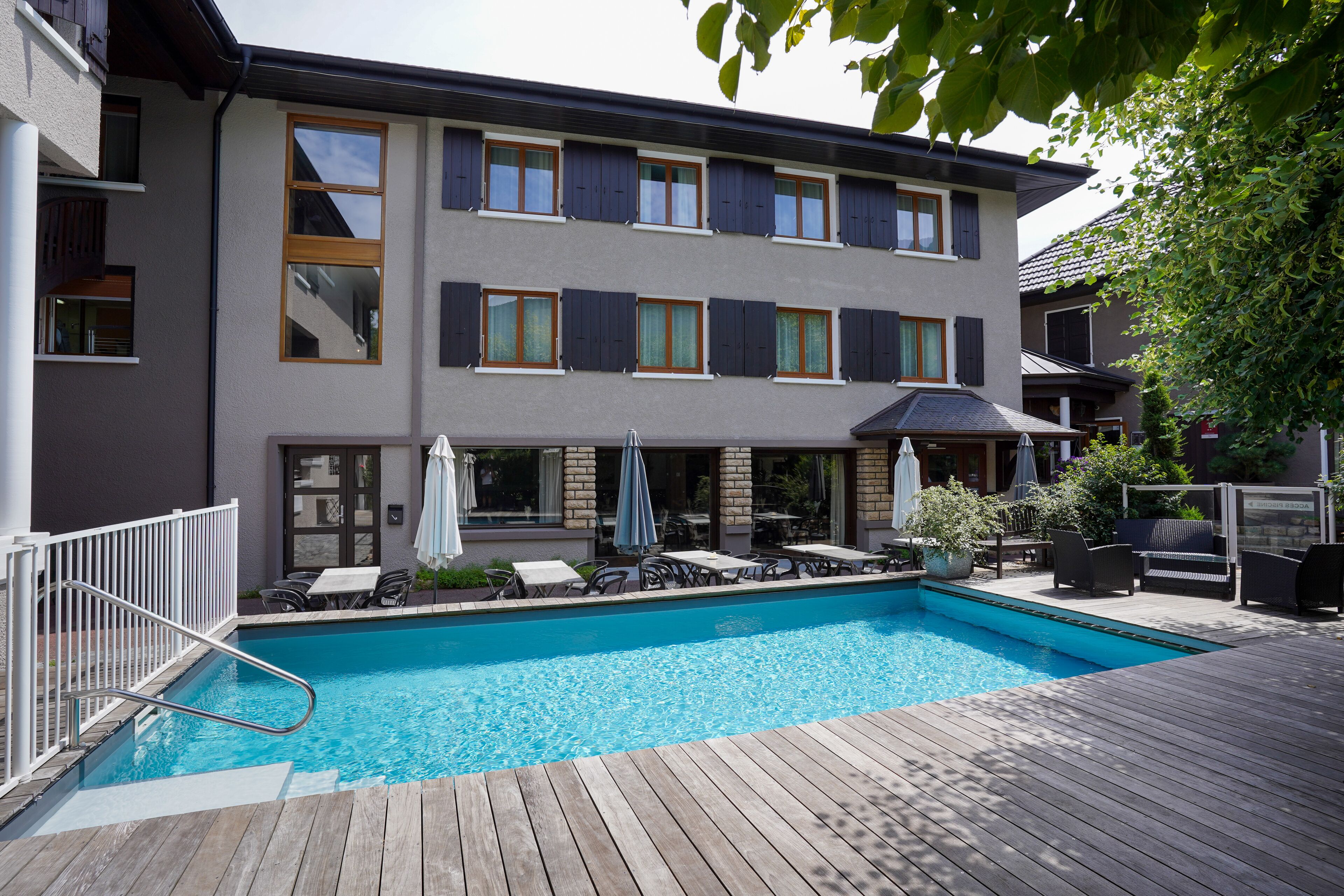 A modern building with a swimming pool, outdoor seating, and a deck.