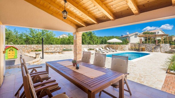 Eine Außenpatio mit Pool, Holzmöbeln und einer Steinmauer.