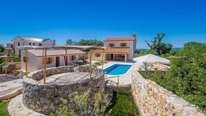 Eine Villa mit Pool, Steinmauern und Meerblick.