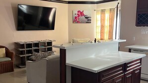 A modern kitchen with a central island, a built-in oven, and a flat-screen TV mounted on the wall. - Island Turquoise Rental- Spacious Two bedroom & 2 Bathroom (Providenciales)