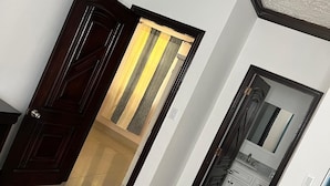 A hotel room with a large bed, a bathroom with a mirror and sink, and a kitchen area. - Island Turquoise Rental- Spacious Two bedroom & 2 Bathroom (Providenciales)