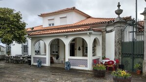 A white building with a tiled roof and arched windows. There are potted plants in front and a gated entrance. - Casa da Real Companhia (Lamego)