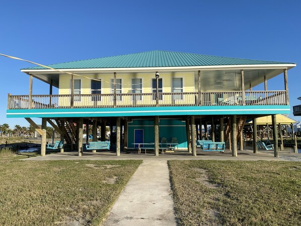 A two-story building with a balcony, wooden pillars, and a concrete pathway. - Spectacular Water Front Home, Lighted/Night Fishing, 500 Lb Ice Machine (Grand Isle)