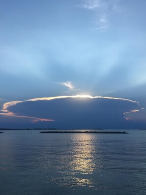 A calm sea with sunlight reflecting off the water, a clear sky, and a distant landmass. - Spectacular Water Front Home, Lighted/Night Fishing, 500 Lb Ice Machine (Grand Isle)
