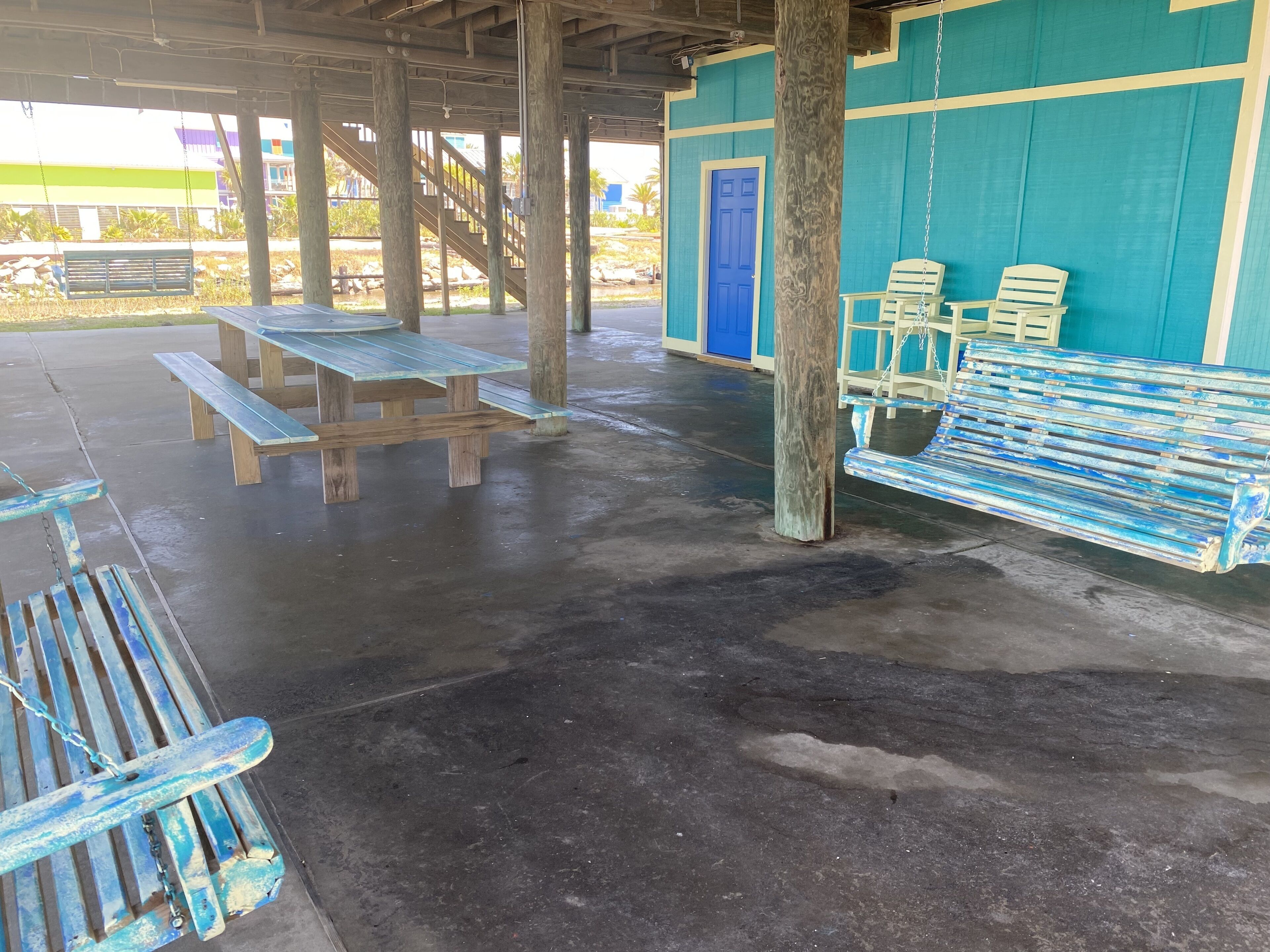 An outdoor covered area with picnic tables, benches, and a swing set.