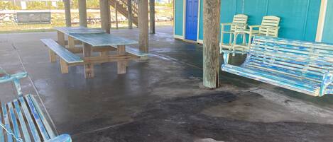 An outdoor covered area with picnic tables, benches, and a swing set.