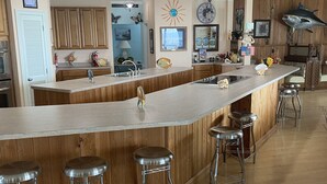 Cozinha com uma ilha grande, armários de madeira e banquetas.