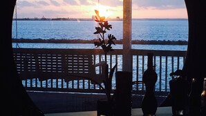 A view from a covered outdoor area with a railing, overlooking a body of water and a sunset. - Spectacular Water Front Home, Lighted/Night Fishing, 500 Lb Ice Machine (Grand Isle)
