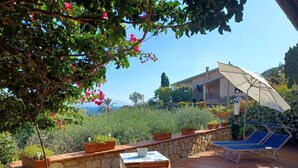 An outdoor patio with a table and chairs, potted plants, and a view of a building and landscape. - CASA MARGOT (RELAX WITH VISTA), independent, 300mt from the sea and the beach (Isola del Giglio)