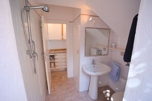 Et badeværelse med bruser, vask og toilet.
