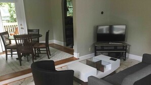 Un salon comprenant un canapé, une table basse, un téléviseur et un coin repas avec des chaises et une table.