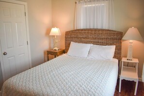 A neatly made bed with a white quilt, a wicker headboard, and two bedside lamps. - Oceanfront duplex sleeping 6-breathtaking views of Nantucket Sound (Dennis Port)