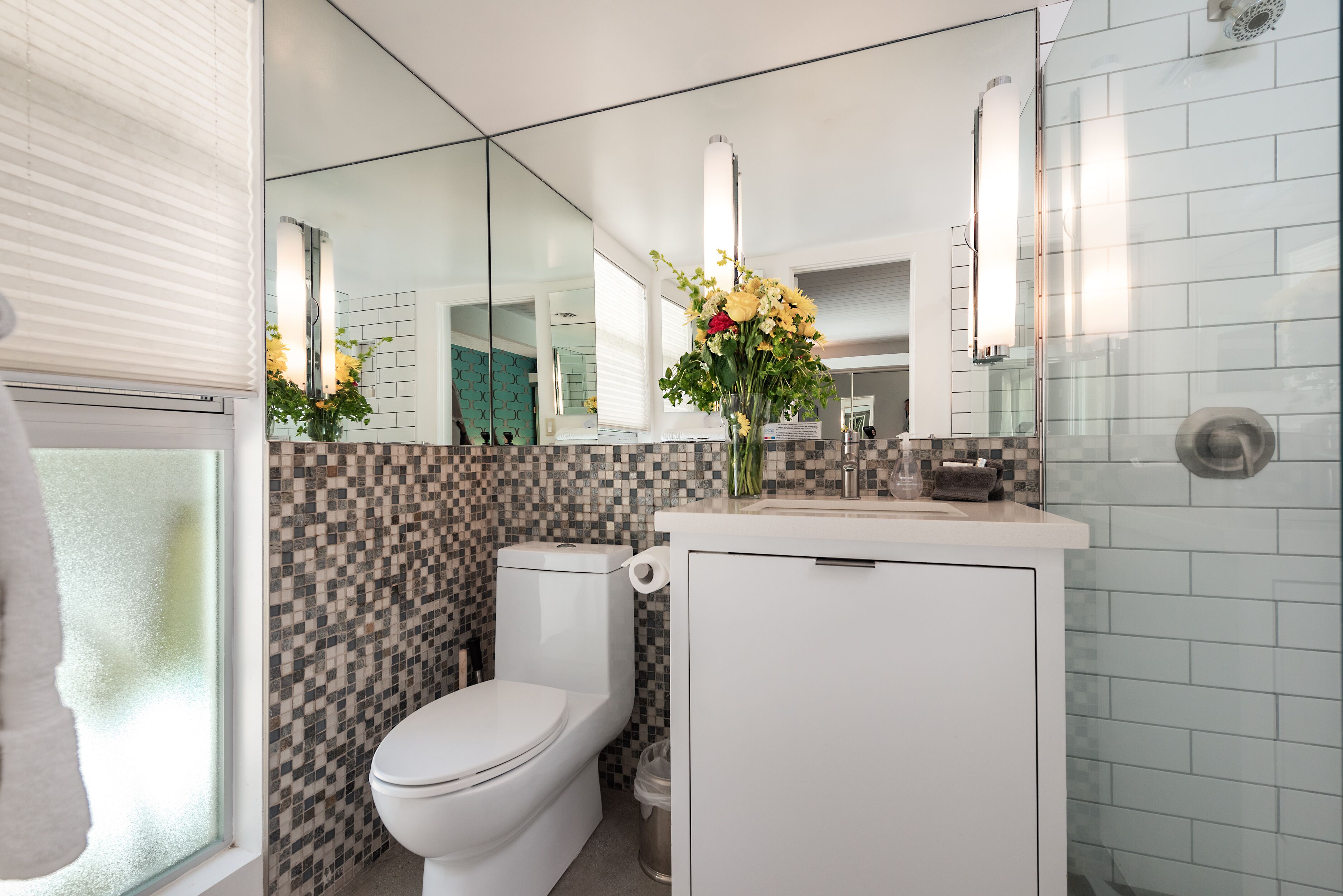 Un baño moderno con inodoro, lavamanos y espejo.