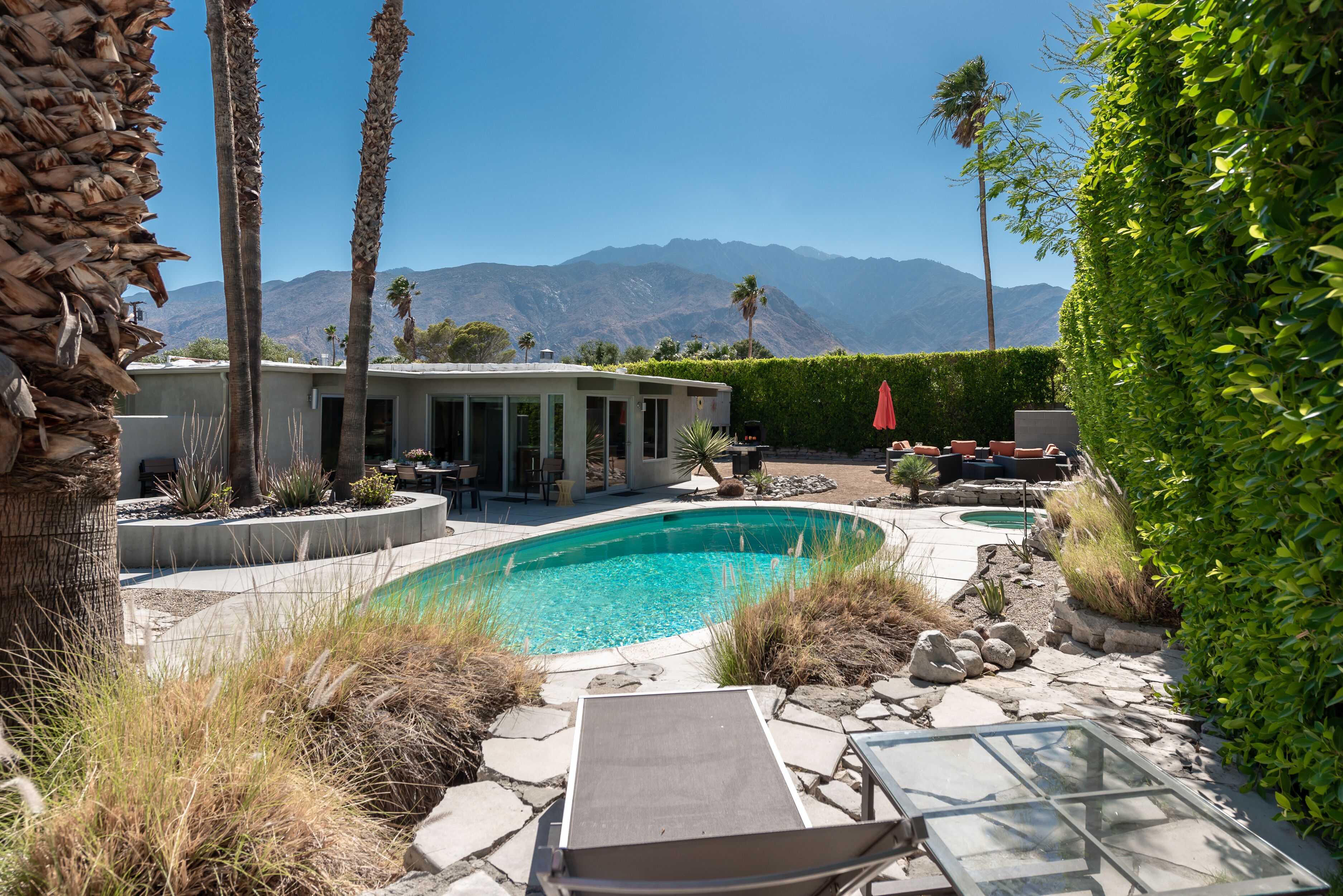 A pool area with a curved pool, lounge chairs, and a view of mountains in the background.