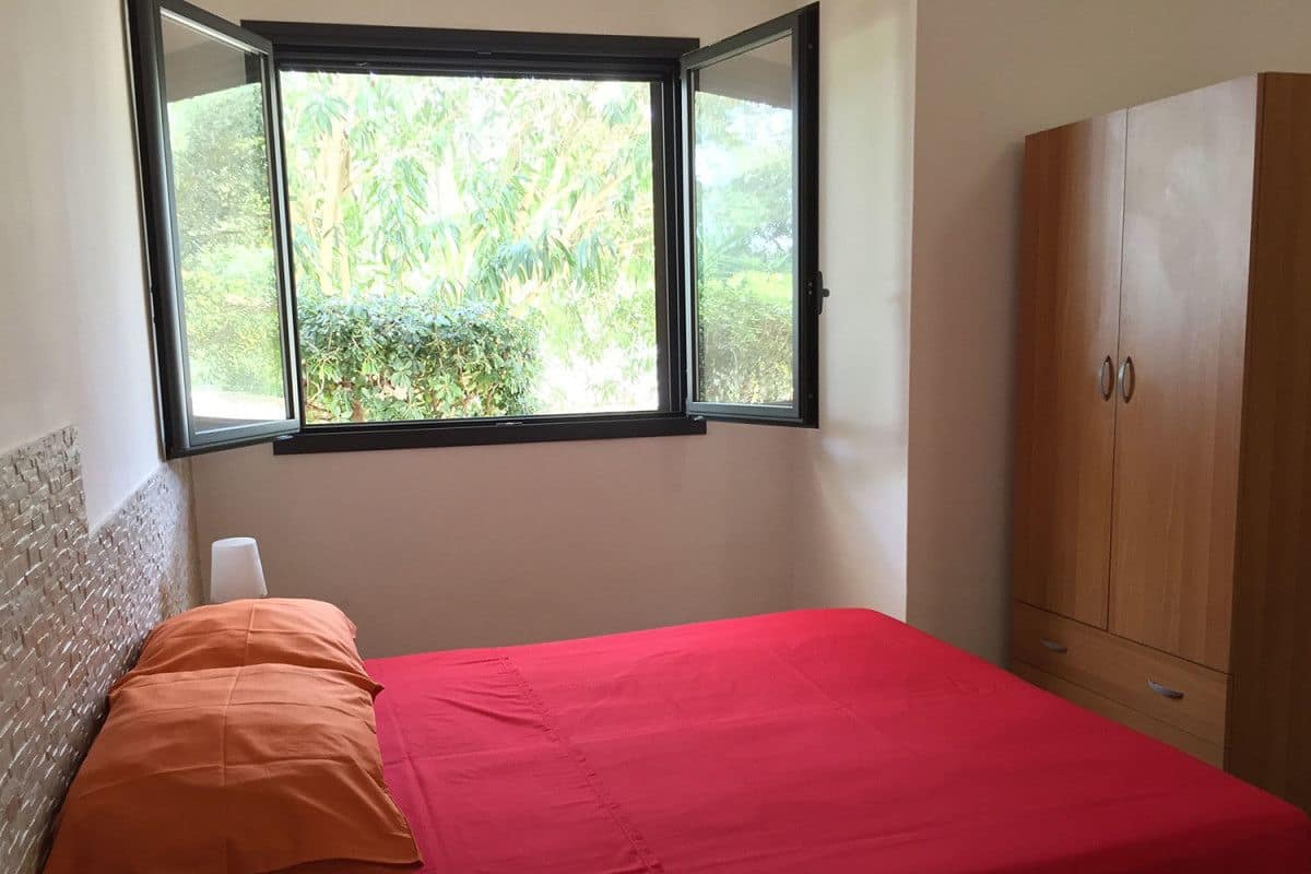 Une chambre avec un lit, une fenêtre et une armoire.