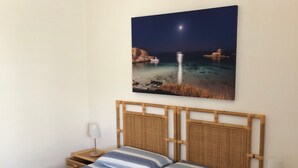 A bed with a striped bedspread, wooden headboard, and two bedside tables with lamps. - La Palude del Conte (Porto Cesareo)