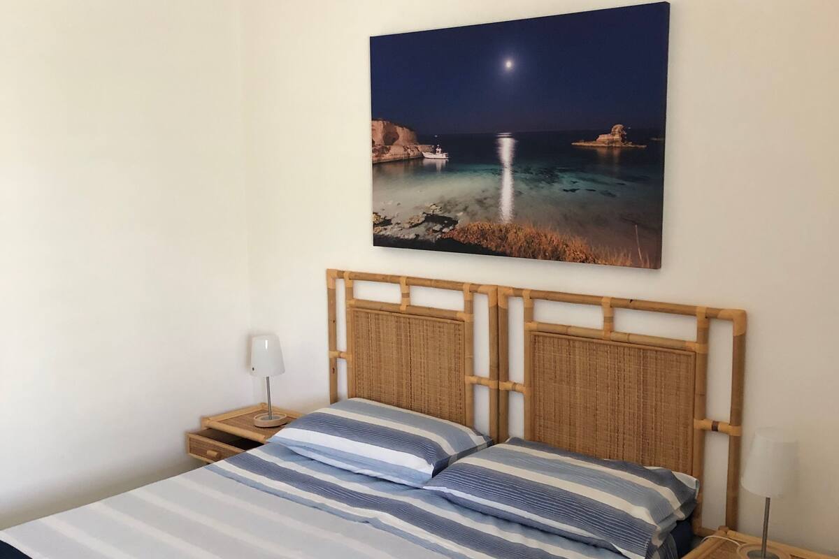 Un lit avec une couvre-lit à rayures, une tête de lit en bois et deux tables de chevet avec des lampes.