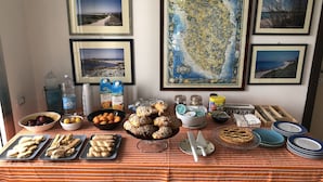 A buffet table with various food items, water bottles, and framed pictures on the wall. - La Palude del Conte (Porto Cesareo)