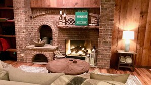 A cozy living room with a brick fireplace, wooden shelves, and a comfortable seating area. - Highlands Happy Place (Highlands)