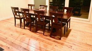 A dining area with a wooden table and chairs, framed botanical prints on the wall, and a view through a glass door. - Highlands Happy Place (Highlands)