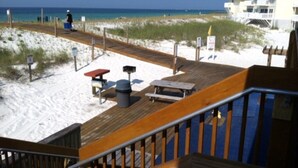 Eine Holzterrasse mit Bank und Picknicktisch, mit Blick auf einen Sandstrand und den Ozean.