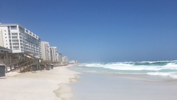 Ein Strand mit einer Reihe weißer Gebäude und blauem Himmel.