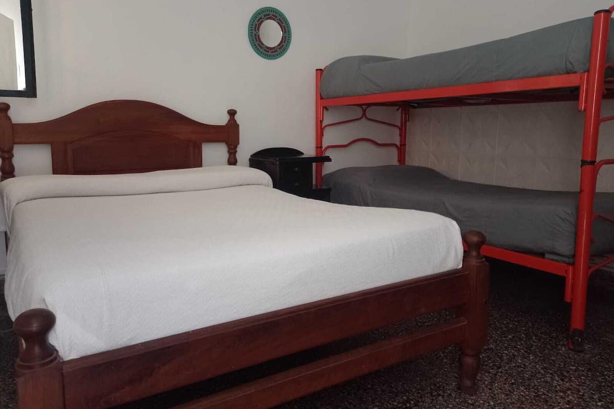 A room with a wooden bed and a red bunk bed.