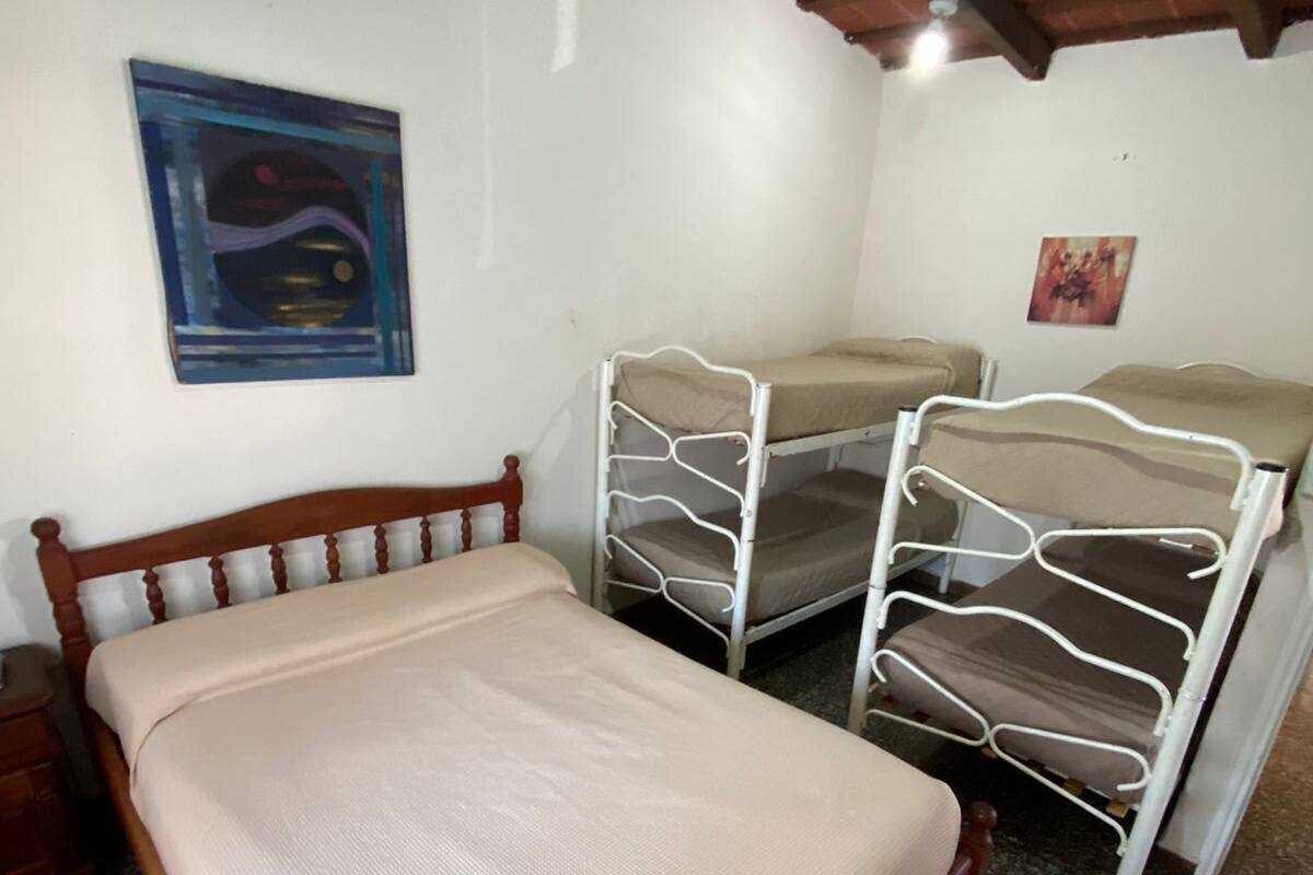 A room with a wooden bed, two bunk beds, a small wooden nightstand, and a ceiling with exposed beams.