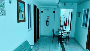 A hallway with a reception desk, a fire extinguisher, and a seating area with chairs and a table.