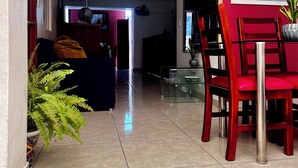 A hallway with a dining area featuring red chairs and a glass table.