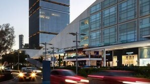 A modern building with a glass facade and a tall, rectangular tower.