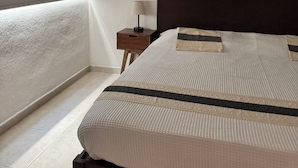 A bedroom with a bed, a nightstand, a lamp, and macramé wall hangings.