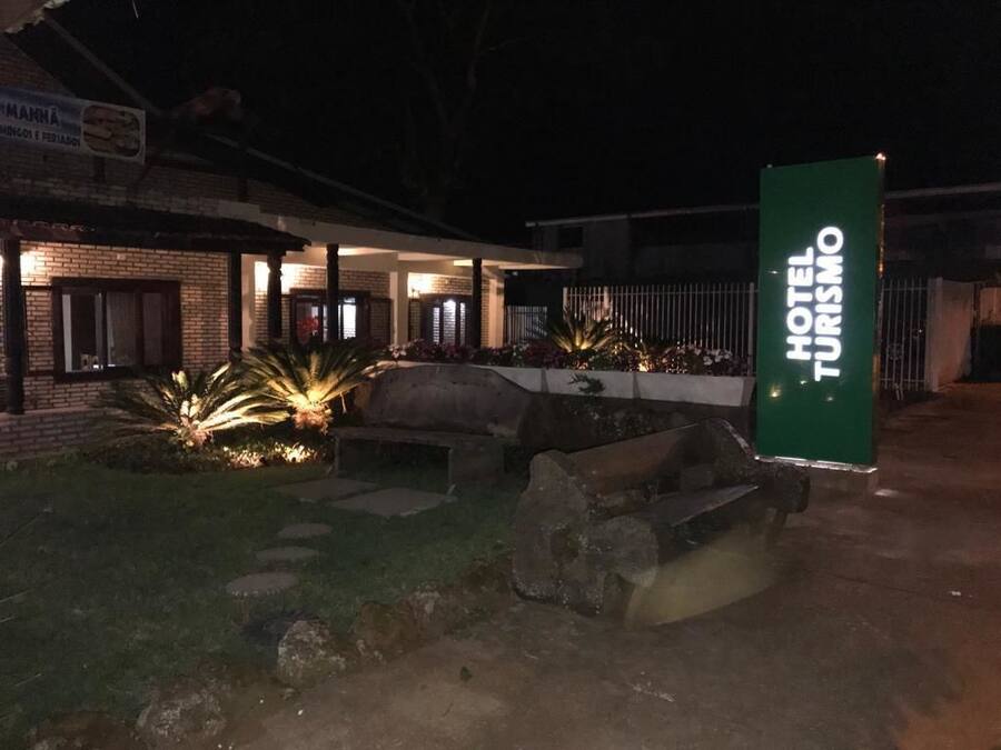Entrada de hotel con un letrero que dice "HOTEL TURISMO" y un edificio de ladrillo con un patio cubierto.