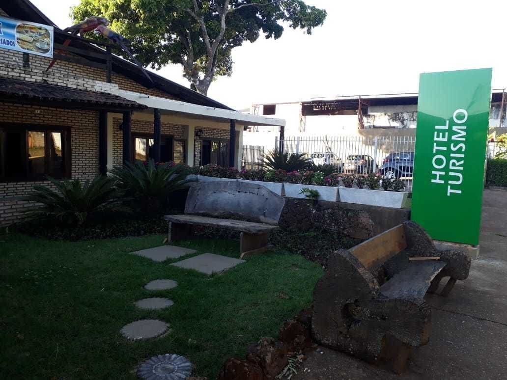 A hotel entrance with a green sign, a bench, and a small garden area with stepping stones.