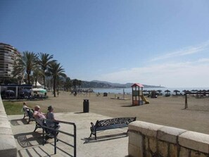 A beach with benches, a lifeguard tower, and palm trees.