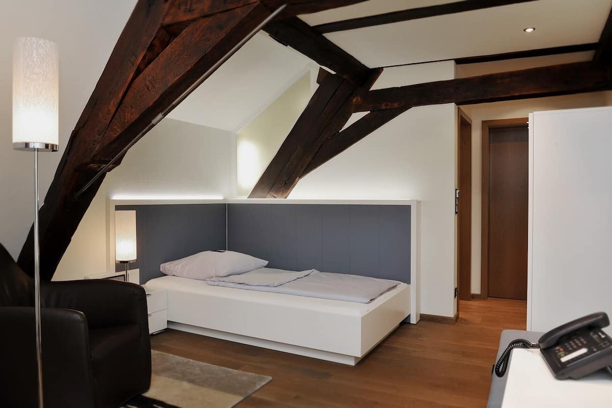 Un dormitorio con cama, un escritorio y teléfono, y una puerta.