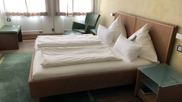 Habitación de hotel con una cama grande, dos mesitas de noche, una silla verde y una lámpara.