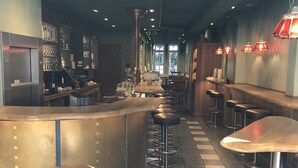 A bar area with stools, a counter, and shelves with glasses and bottles. - CENTRINUM Altstadt-Hotel (Melsungen)