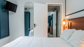 Ein Hotelzimmer mit Bett, Wandfernseher, Kleiderschrank und einer Tür zum Badezimmer.