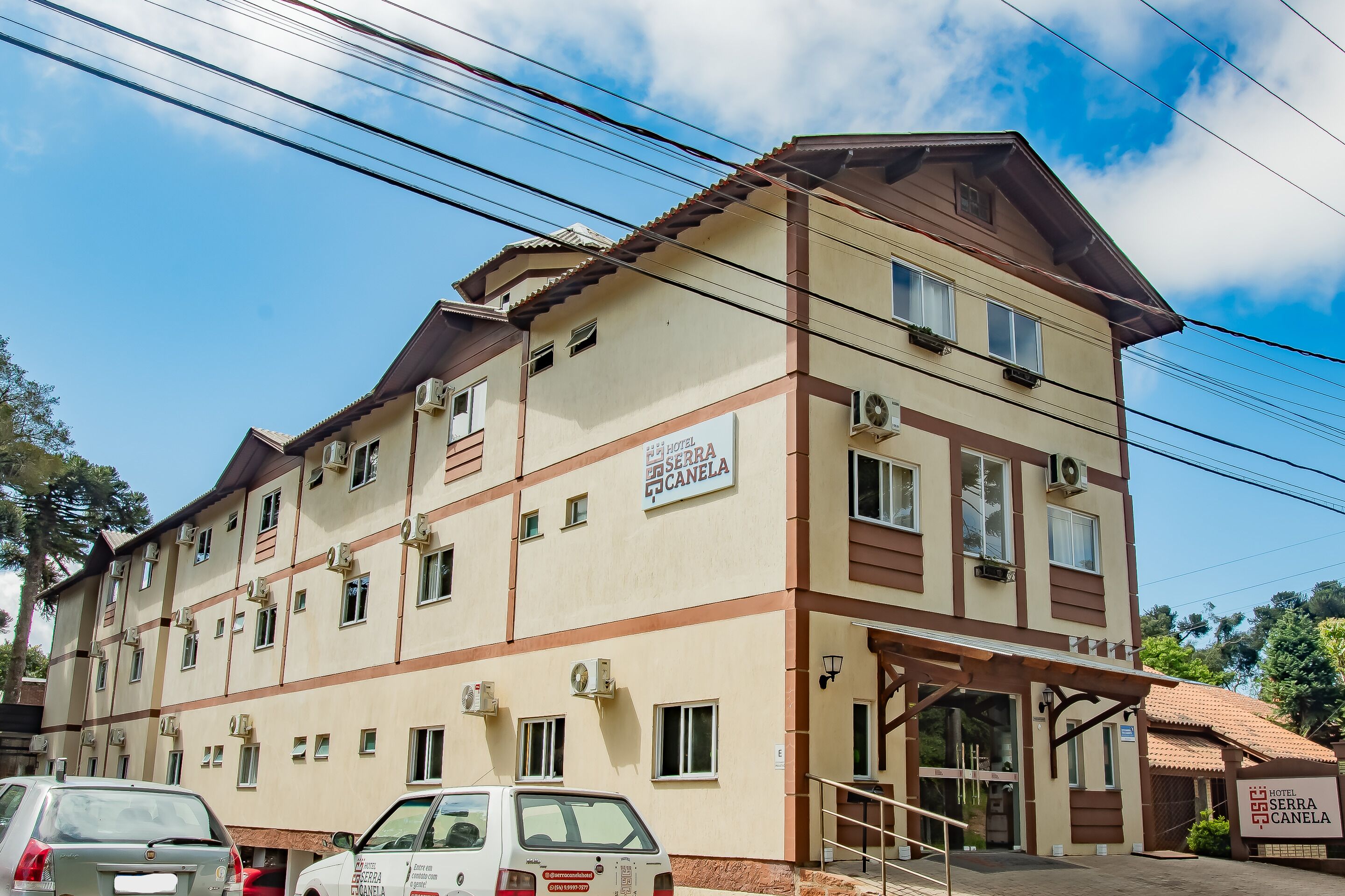 A multi-story hotel with a beige facade, multiple windows, and a sign indicating it is the "Hotel Serra Canela."