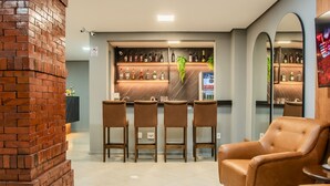 Eine Bar mit Backsteinwand, mehreren Barhocker und einem Ledersessel.